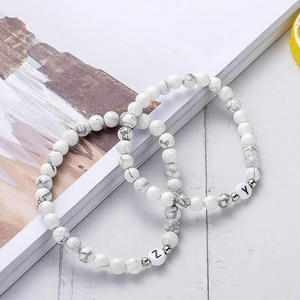 Bracelets en perles de turquoise blanche de 6mm avec lettres Z et Y sur un magazine