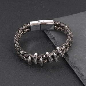 Macro detail of men's braided leather bracelet with vintage metal charms and magnetic clasp