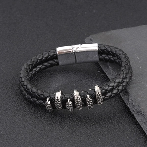 Close-up of double-strand braided leather bracelet with silver metal claw charms and buckle