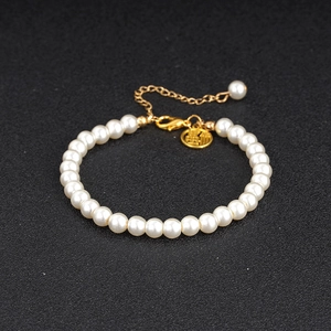 Vintage pearl bracelet with gold Fu character pendant and lobster clasp on black background