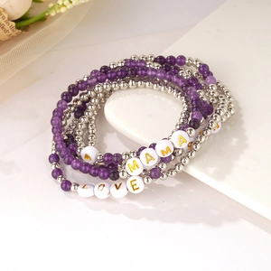 Dettaglio di bracciali boho con lettere MAMA e LOVE su vassoio in marmo pregiato