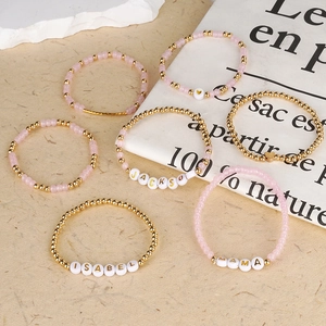 Dettaglio di braccialetti bohémien con perline dorate e nomi personalizzati sulle perline