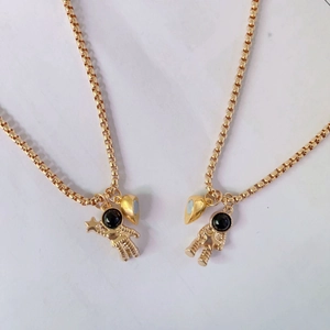 Detailansicht der Astronauten-Anhänger und magnetischen Herz-Charms auf Goldketten