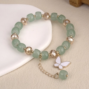 Detail of beaded bracelet with light green frosted beads and a white butterfly charm