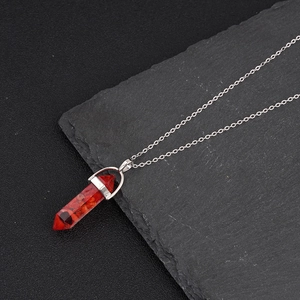 Hexagonal red crystal stone pendant necklace on a natural dark slate stone surface