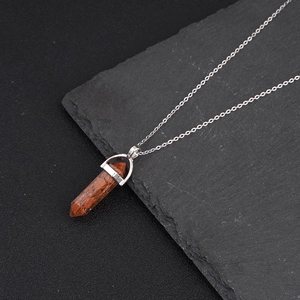 Hexagonal crystal pillar pendant necklace with silver chain on dark stone background