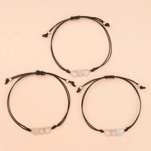 Dettaglio di tre ciondoli a cuore intrecciati su braccialetti regolabili in cordino nero