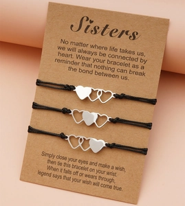 Vista dettagliata di tre braccialetti cuore per sorelle su un cartoncino kraft con citazioni