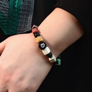 Detail of colorful volcanic stone beaded bracelet with black billiard number 8 bead charm