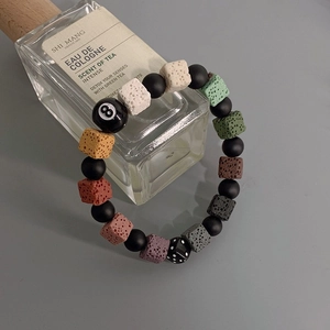 Detail of colorful volcanic stone bracelet with billiards 8-ball and dice on perfume bottle