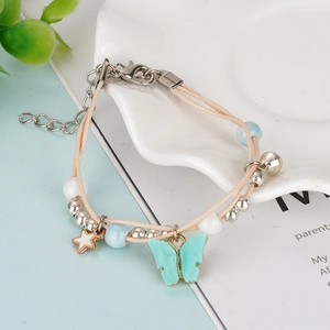 Handmade woven nautical anchor bracelet with butterfly and star charms on ceramic plate