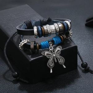 Detail of multi-layer leather bracelet featuring a silver butterfly pendant and blue beads