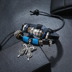 Detailed macro view of woven leather bracelet with alloy butterfly charm and blue thread