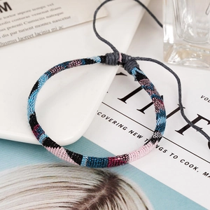 Detail of bohemian woven bracelet with colorful cotton threads and adjustable cord on tray