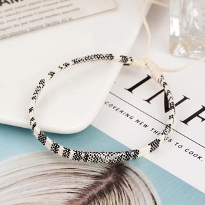 Close-up of a handmade bohemian cotton linen woven bracelet with black white patterns