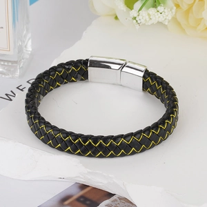 Detail of black braided leather bracelet with yellow stitching and silver magnetic clasp