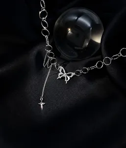 Macro shot of silver butterfly and star pendant on metallic chain over black silk