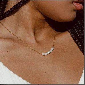 Collar minimalista de oro con cinco perlas blancas en un diseño de barra horizontal