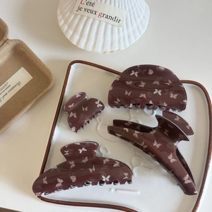4-piece set of brown hair claws with butterfly prints on a decorative white porcelain plate