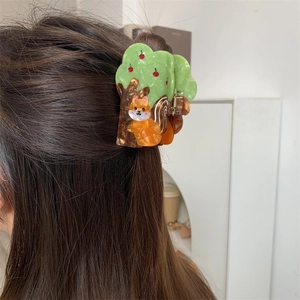 Detail of creative squirrel and tree acetate hair claw clip worn on brown hair