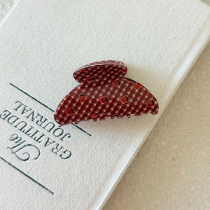 Macro detail of red plaid butterfly hair claw with strawberry patterns on a journal