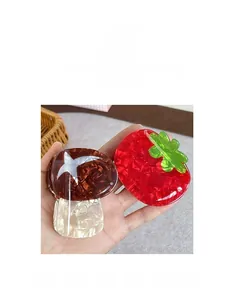 Detalle de pinzas para el cabello con forma de hongo y tomate en acetato de colores