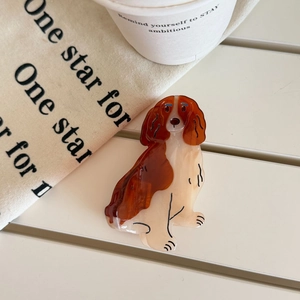 Detail of a brown marble acetate dog-shaped hair claw on a white wooden table background