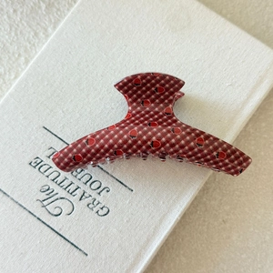 Detail of red plaid claw clip with black strawberry prints on a journal book