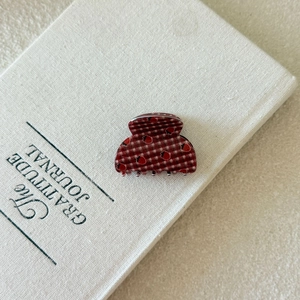 Detail shot of a red checkered hair claw clip with strawberry prints on a journal