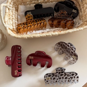 Elegant leopard print hair claws in burgundy and black colors in a woven basket