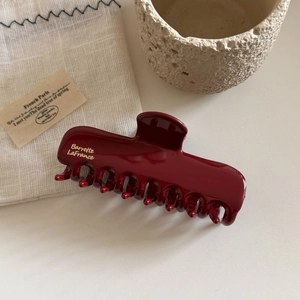 Close-up of elegant burgundy resin hair claw clip with golden Barrette LaFrance lettering