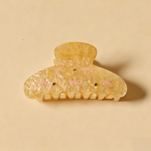 Pince à cheveux crème élégante avec nœuds roses et strass sur texture marbrée