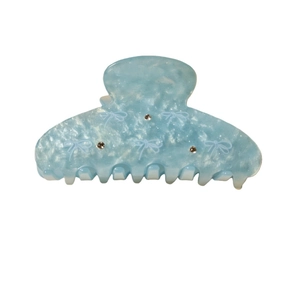 Pince à cheveux en acrylique bleu marbré avec motif nœud et strass étincelants