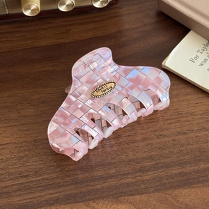 Gros plan d'une pince à cheveux à damier rose avec plaque dorée sur bureau en bois