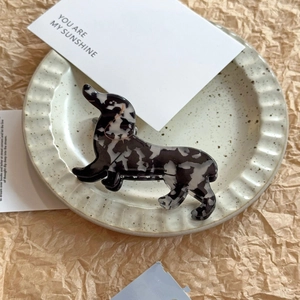 Close-up of dachshund-shaped hair claw clip with black and white patterns on a tray