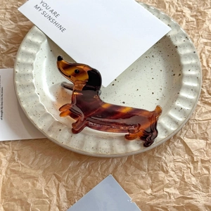 Detailed view of dachshund-shaped amber tortoiseshell claw clip on a decorative tray
