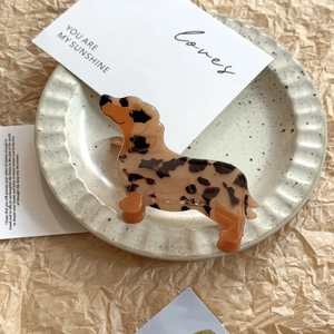 Detail view of a leopard print dachshund hair claw clip on a decorative ceramic plate