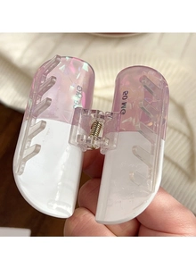 Detail shot of the capsule-shaped hair claw featuring 20 MG print and lilac dual-color finish
