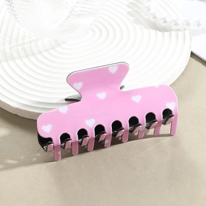 Detail einer großen rosa Haarspange mit weißem Herzmuster auf Keramikteller