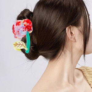 Pince à cheveux fleur en acétate marbré rouge et blanc portée sur un chignon chic