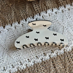 Detailed view of cream acetate hair claw clip featuring black terrier dog silhouettes