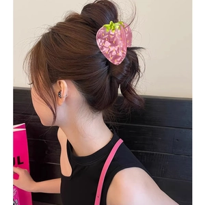 Vue détaillée de la pince à cheveux fraise rose portée sur un chignon élégant