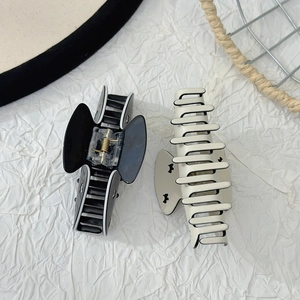 Close-up of black and white acetate hair claws with contrast edging on a textured background