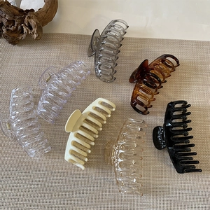 Set of six large amber-style hair claw clips in assorted colors on a neutral textured mat