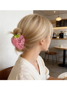 Détail d'une jolie pince à cheveux fraise rose coiffée dans le chignon d'un modèle