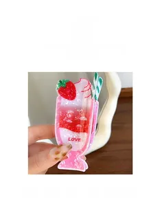 Détail d'une pince à cheveux rose en forme de milkshake à la fraise avec texte Love