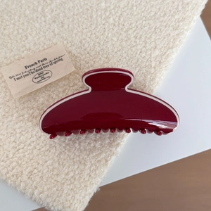 Detailed macro view of a burgundy red shark hair claw clip on soft beige fleece texture