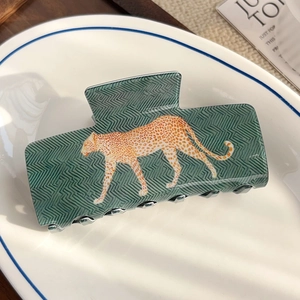 Détail d'une pince à cheveux motif léopard vert sur une assiette décorative en porcelaine