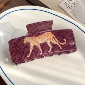 Détail d'une grande pince à cheveux violette avec motif léopard sur une assiette