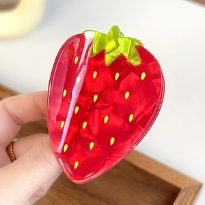 Vue détaillée d'une pince à cheveux fraise avec finition rouge brillante et feuilles vertes